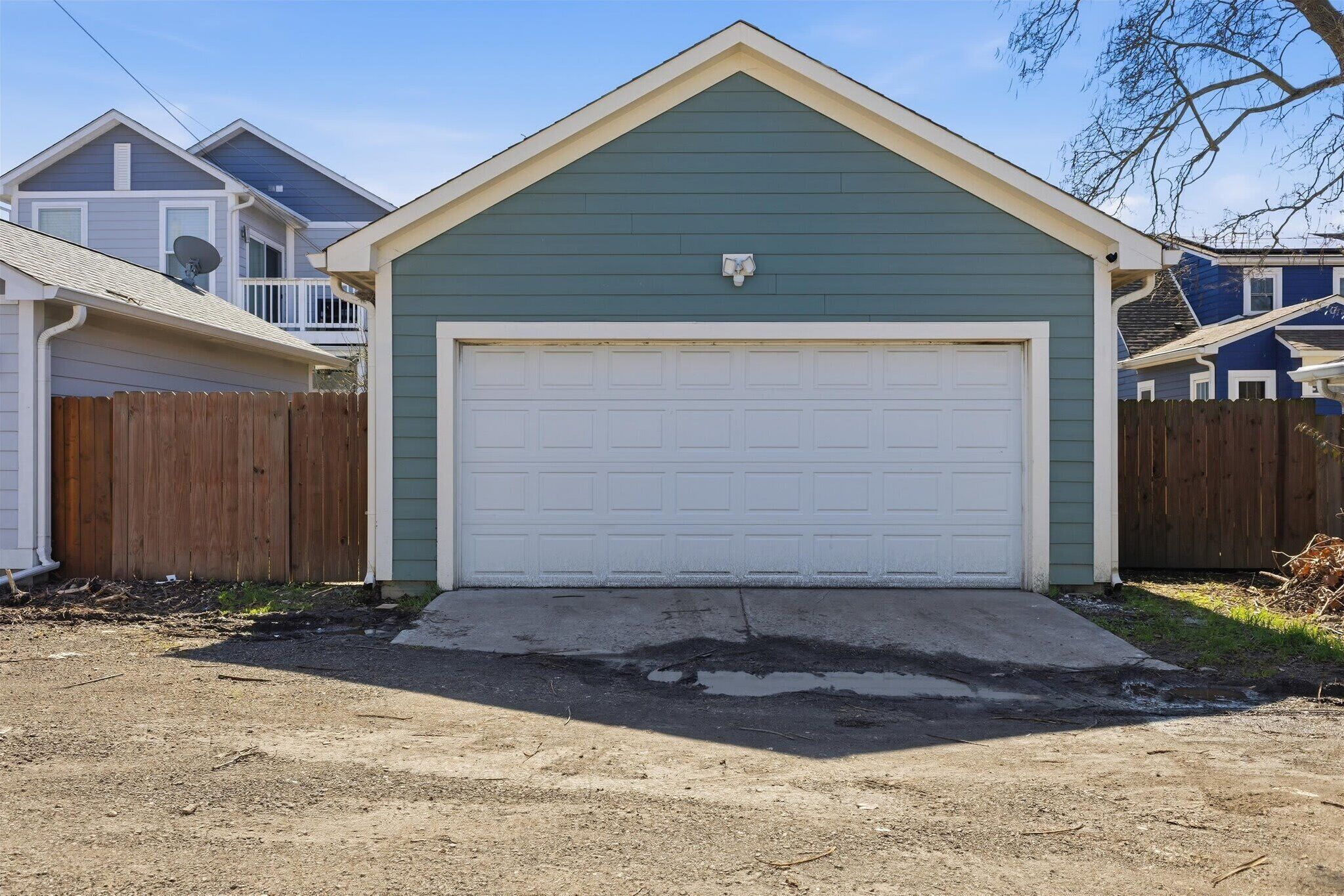 A single-story house with a garage, a wooden fence, and a clear sky.