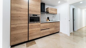 A modern kitchen with wooden cabinetry, stainless steel appliances, and a tiled backsplash. - Apartment With Pool in the Heart of Marbella (Marbella)
