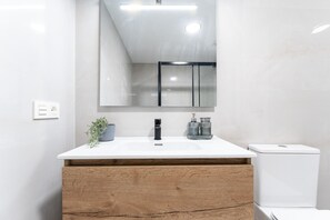 Ein modernes Badezimmer mit einem weißen Waschbecken, einem Holz-Waschtisch und einer weißen Toilette.