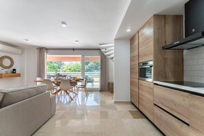 Eine moderne Küche mit Holzschränken, einem Einbauofen und einem Essbereich mit Tisch und Stühlen.