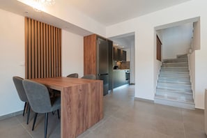 Een moderne keuken met een inbouwkoelkast, een eethoek met een houten tafel en stoelen, en een trap die naar een ander niveau leidt.