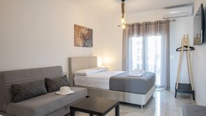 Une chambre d’hôtel moderne, équipée d’un lit, d’un canapé, d’une petite table, d’un tableau au mur et d’un téléviseur fixé au mur.