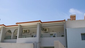Un bâtiment doté d’un toit recouvert de tuiles rouges, de nombreux balcons et de climatiseurs.