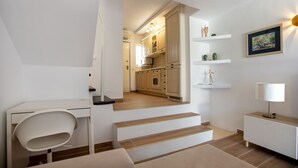 Ein modernes Interieur mit einer Treppe, die zu einer Küche führt, einem Schreibtisch mit Stuhl und einem Nachttisch mit Lampe.