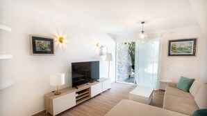 Ein modernes Wohnzimmer mit Fernseher, Sofa und Kunstwerken an den Wänden.