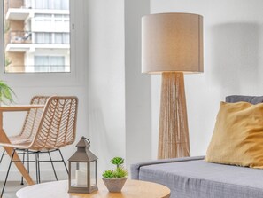 A modern living room with a round table, wicker chairs, a floor lamp, a sofa with a cushion, and a small potted plant. - Sea View Apartment in Fuengirola (Fuengirola)