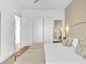 A bedroom with a bed, bedside tables, a nightstand, a mirror, and a door. - Sea View Apartment in Fuengirola (Fuengirola)