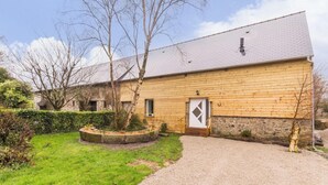 A wooden building with a stone foundation, a gravel driveway, and a landscaped garden with a circular flower bed. - Peaceful country house - 4 guests (SAINT SAUVEUR VILLAGES)