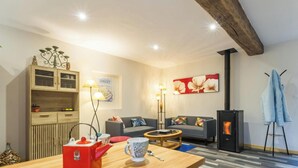A living room with a sofa, a coffee table, a cabinet, a fireplace, and a wall with a floral painting. - Peaceful country house - 4 guests (SAINT SAUVEUR VILLAGES)