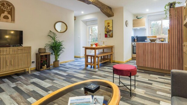 A living room with a TV, a wooden cabinet, a dining table, and a kitchen area with a wooden counter. - Peaceful country house - 4 guests (SAINT SAUVEUR VILLAGES)