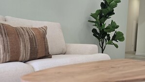 Ett modernt vardagsrum med en soffa, ett soffbord i trä och en krukväxt.
