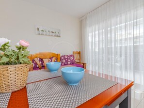 A dining area with a table, chairs, a basket of flowers, and a sofa with cushions. - Renovated apartment central Salou - 4 guests (Salou)