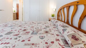 Un dormitorio con una cama, cabecera de madera, mesita de noche, lámpara de pared y una puerta.