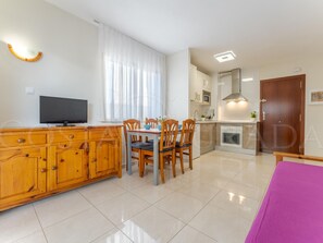 Eine moderne Küche mit Essbereich, Fernseher und Holzschrank.
