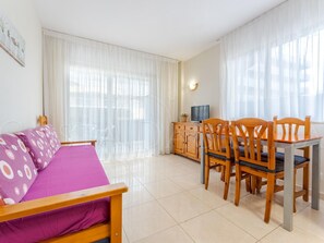 Une pièce comprenant un canapé, une table à manger avec des chaises, un téléviseur et un meuble.