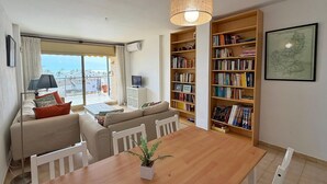 En moderne stue med spisebord, sofa, reol og udsigt over byen.