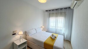 Et hotelværelse med seng, sengeborde, lampe, gardiner og en klimaanlæg.