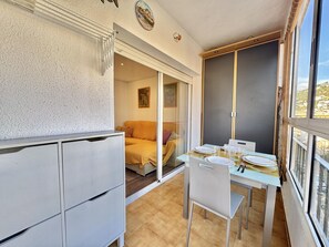 A compact room with a dining table set for two, a sofa, and a sliding glass door leading to a balcony. - Central, quiet apartment - 4 guests (Roses)