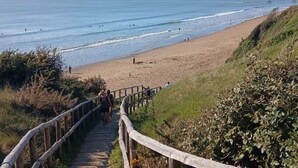 Une plage avec un escalier en bois qui descend vers le rivage, entourée de verdure.