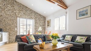 Un salon avec un mur en pierre, un canapé en cuir noir, une table basse en bois et un tableau accroché au mur.