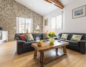 A living room with a stone wall, a black leather sofa, a wooden coffee table, and a painting on the wall. - Apartment in the center of La Plaine-sur-Mer (La Plaine-sur-Mer)