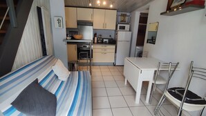 Ein kleines Zimmer mit einem Bett, einem Tisch, einem Stuhl, einer Küchenzeile und einer Treppe.