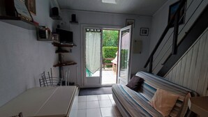 Ein kompakter Wohnbereich mit Esstisch, einer Couch, einem Fernseher und einer Treppe.