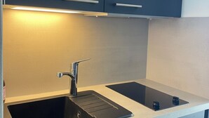 A modern kitchen with a sink, a stovetop, and overhead cabinets. - Bright apartment near the beach - 6 guests (Arzon)