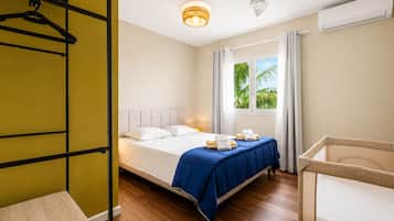 Een hotelkamer met een bed, een plafondventilator, een raam met gordijnen en een wandairconditioner.