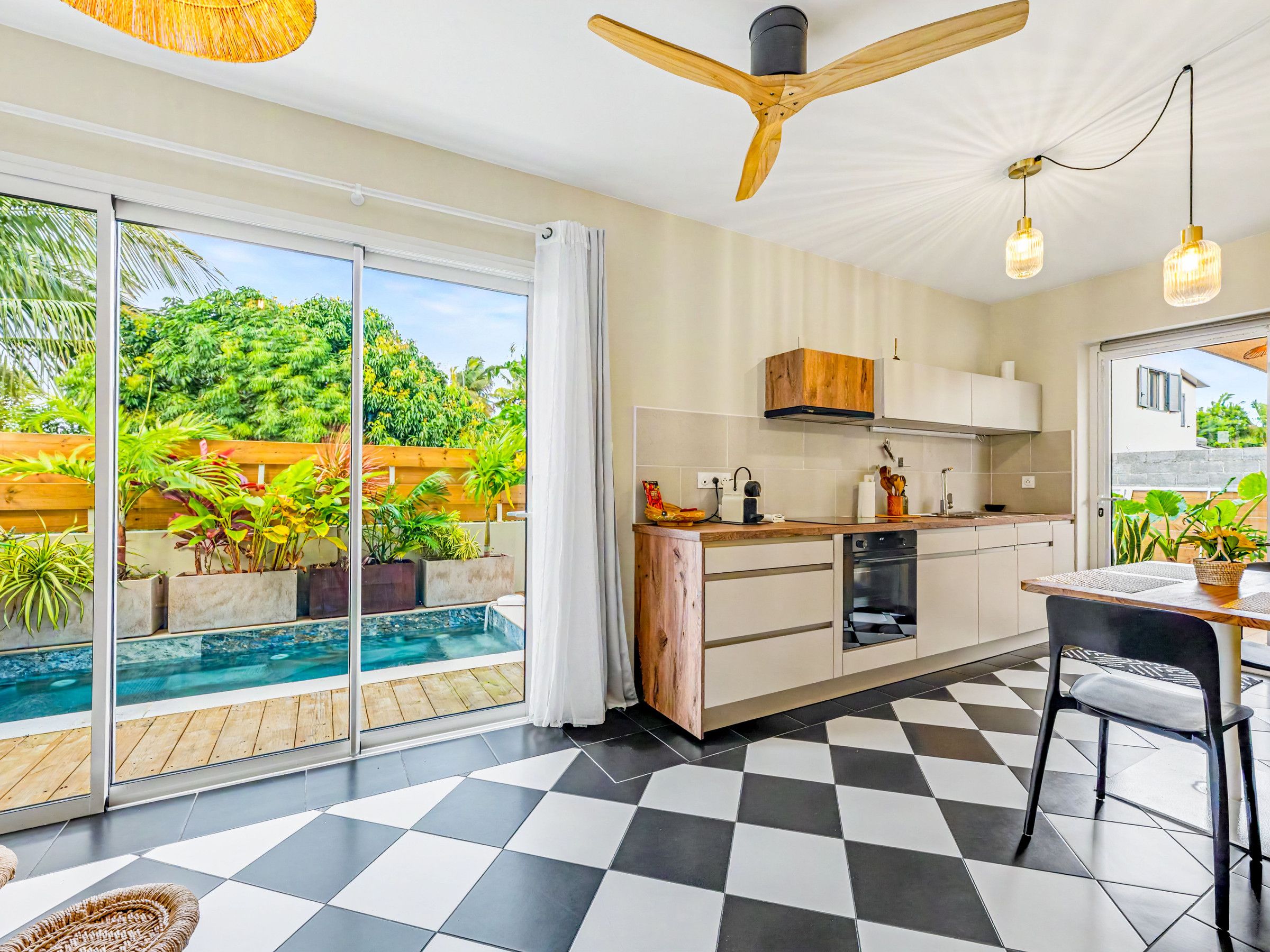 Una cocina moderna con piso a cuadros, horno empotrado y vista a una piscina.