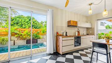 Una cocina moderna con piso a cuadros, horno empotrado y vista a una piscina.