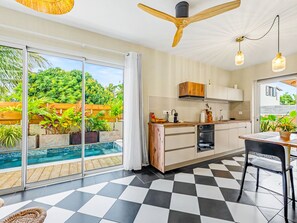 A modern kitchen with a checkered floor, a built-in oven, and a view of a swimming pool. - Villa with private pool - 4 guests (Saint-Joseph)