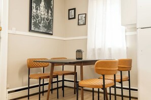 A dining area with a table and chairs, a chandelier, and two framed pictures on the wall.