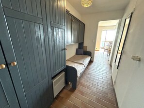 A narrow hallway with a bed, a radiator, and a door. - Apartment with sea view - 4 guests (Six-Fours-les-Plages)