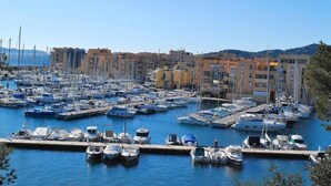 A marina with numerous boats docked, surrounded by multi-story buildings. - Apartment, AC, parking - 4 guests (Bormes-les-Mimosas)