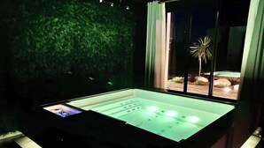 Une pièce dotée d’une vitrine, d’un mur vert et d’une fenêtre donnant sur un palmier et un immeuble.