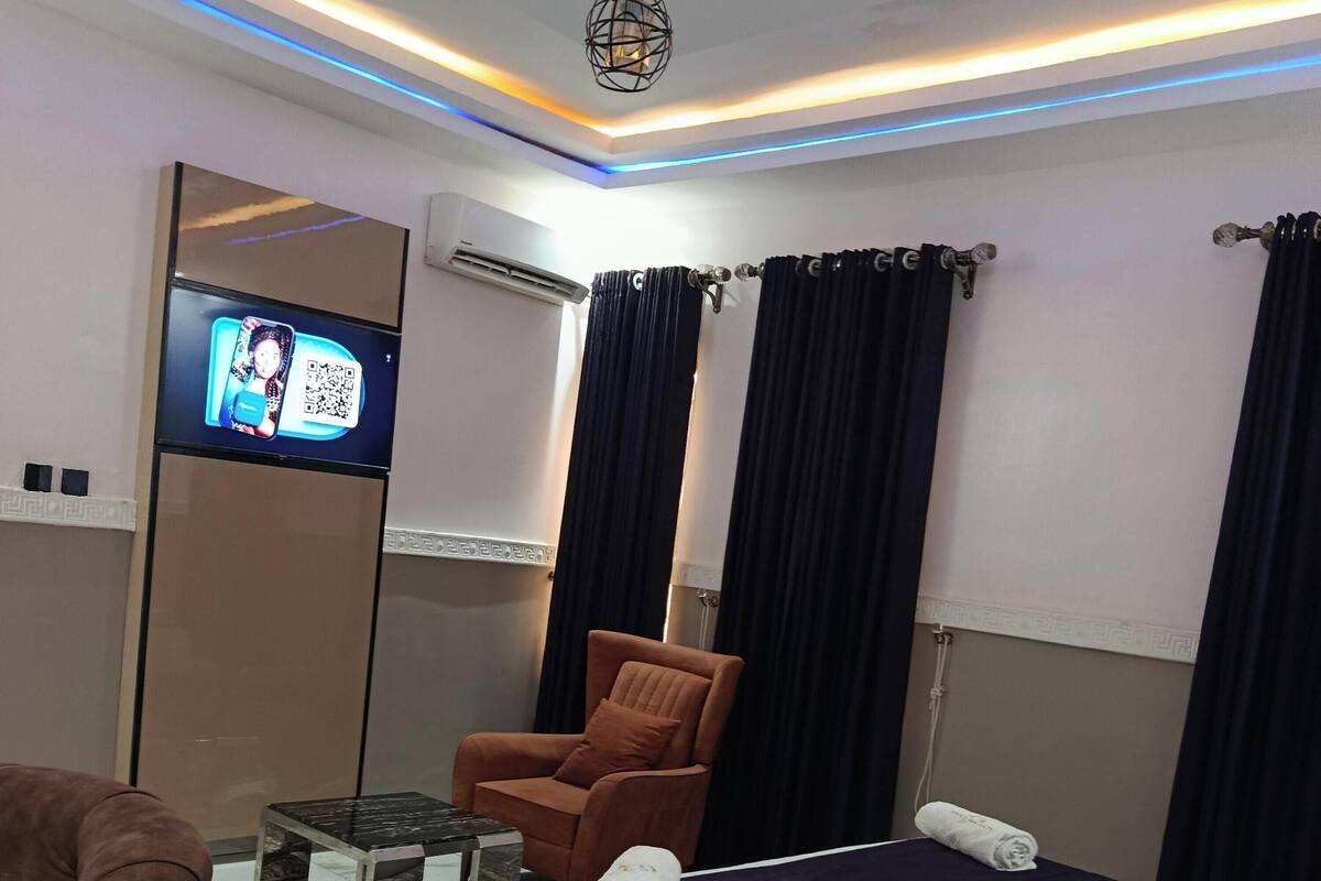 Una habitación de hotel con una cama, un sofá, una silla, un televisor y un equipo de aire acondicionado.