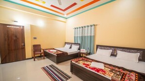 A hotel room with two beds, a wooden door, a chair, and a striped rug. - Omji Ashram - Char Bhuja Dham (Ayodhya)