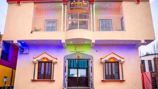 A two-story building with a central entrance, a balcony on the upper floor, and a staircase leading to the entrance. - Omji Ashram - Char Bhuja Dham (Ayodhya)