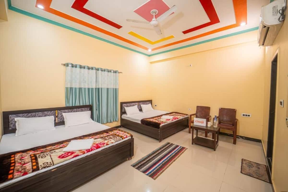 A hotel room with two beds, a ceiling fan, a small table with a sign, and a window with curtains.