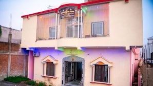 A two-story building with a central entrance, a staircase, and two small windows on the ground floor. - Omji Ashram - Char Bhuja Dham (Ayodhya)