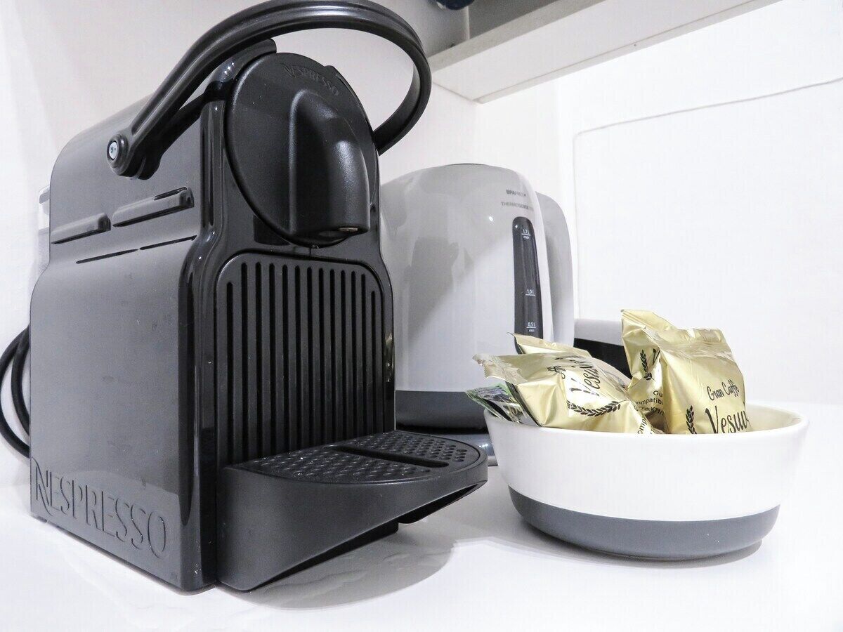 A black Nespresso coffee machine with a bowl of coffee pods.
