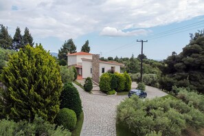 A house with a stone pathway leading to the entrance, surrounded by greenery and trees.