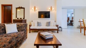 Una sala de estar con un sofá, una mesa de centro con libros, un televisor y una chimenea.