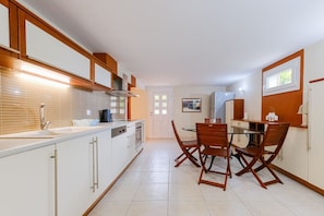 A compact kitchen with white cabinets, a sink, a stove, and a dining area with a table and chairs.