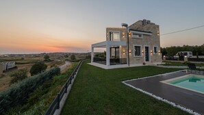 A modern house with a pool, surrounded by a well-maintained lawn and a view of the countryside. - Villa Amelia by Travel Pro - Mouries Halkidiki (Nea Moudania)