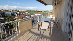 En balkong med ett bord och stolar, utsikt över ett bostadsområde och en byggnad med en beige fasad.