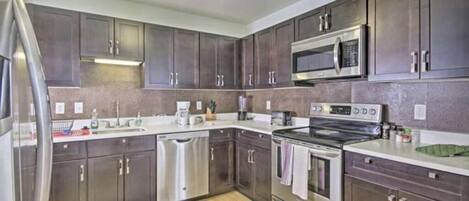 A modern kitchen with dark cabinets, stainless steel appliances, and a central island.