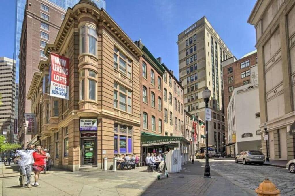 A historic building with a 'NOW LEASING LOFTS' sign, a water street tavern, and a fire hydrant on a cobblestone street.