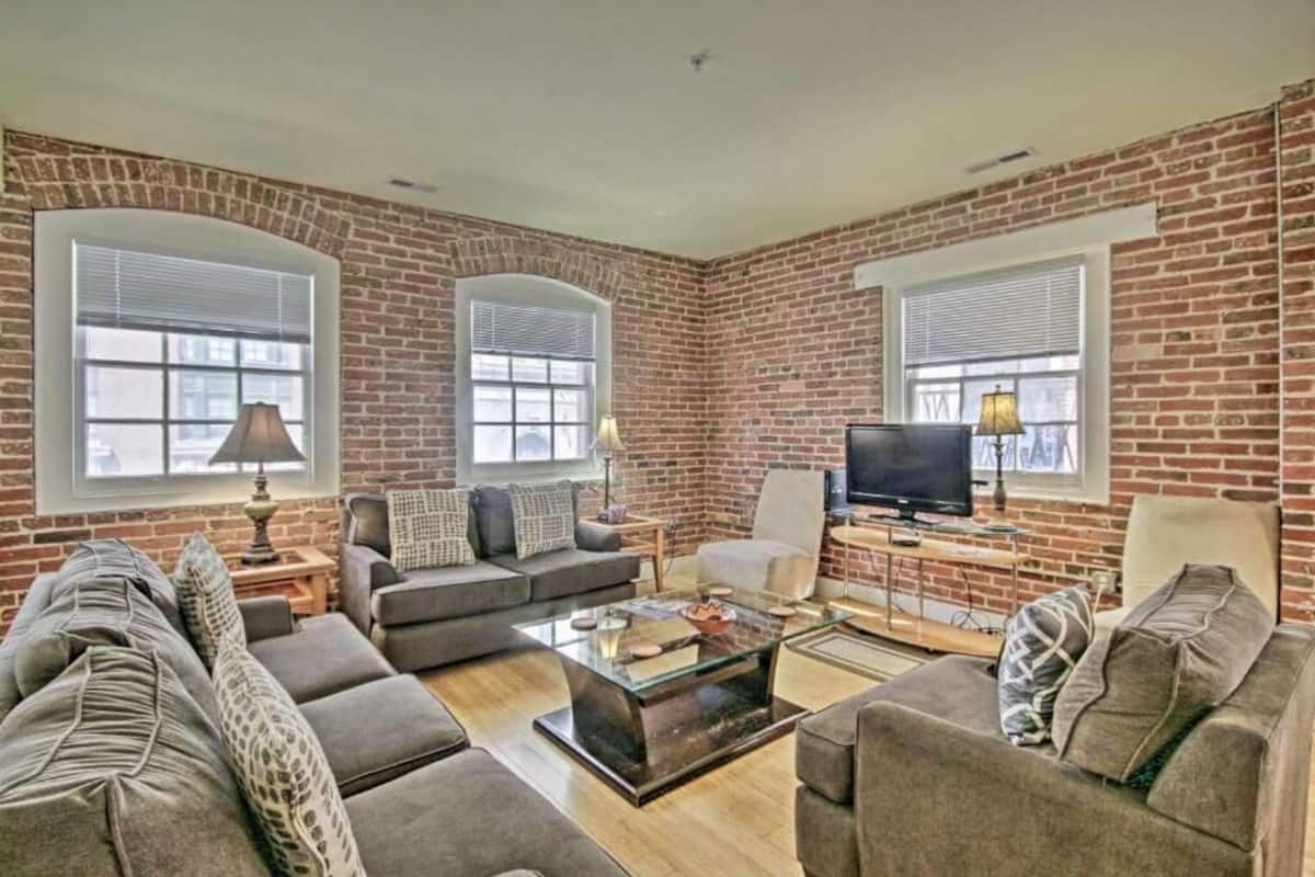 A living room with brick walls, a sofa set, a coffee table, and a television.